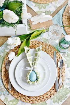 the table is set with white flowers and green napkins, silverware and place settings