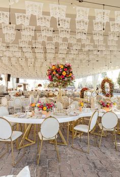 the tables are set up for an event with white linens and floral centerpieces