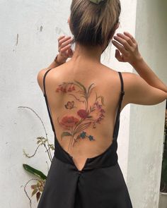 the back of a woman's body with flowers tattooed on her upper and lower back