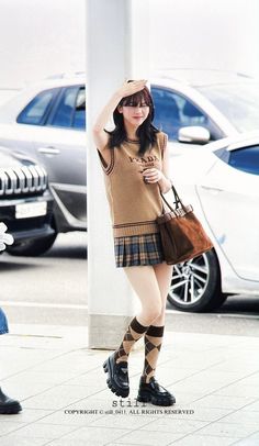 a woman is standing on the sidewalk with her hand in her hair and holding a purse