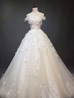 a white wedding dress on display in front of a black background with an image of the bride's gown