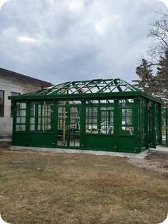 a small green building sitting on top of a grass covered field