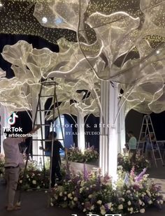 people are working on an artificial tree in the middle of a room filled with flowers