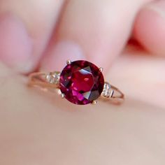 a woman's hand holding a ring with a large pink stone in the middle