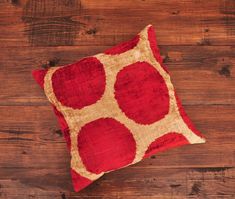 a red and beige pillow sitting on top of a wooden floor