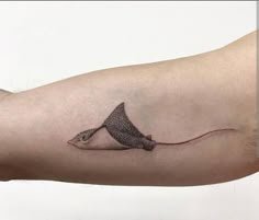 a man's arm with a small tattoo of a shark on the back of it