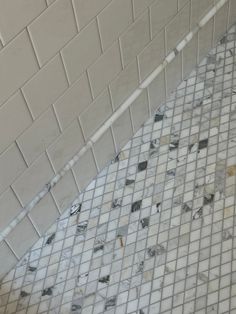 a white and black tiled floor in a bathroom next to a wall with no shower curtain