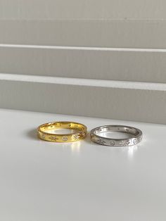 two gold and silver rings sitting on top of a white counter next to each other