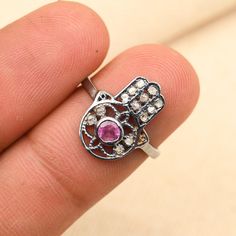 Hamsa Hand Ruby Ring, 925 Sterling Silver Diamond Ring, Protection Symbol Jewelry, Handmade Statement Ring, Ruby Ring, Unique Gift for Her Ring Details Metal: 925 Sterling Silver Main Stone: Natural Main Stone Name: Ruby Style: Art Deco Gross Weight: 2.3 grams Stone Weight: 0.2 carats Diamond Weight: 0.15 carats This Hamsa Hand Ruby Ring, 925 Sterling Silver Diamond Ring, Protection Symbol Jewelry, Handmade Statement Ring, Ruby Ring, Unique Gift for Her. surrounded by a vintage-inspired halo of sparkling pave diamonds. Its timeless Art Deco design makes it an exceptional choice for engagements or as a heartfelt gift for someone special. The radiant green emerald combined with dazzling diamonds creates an elegant and timeless appeal. Whether worn as a statement piece or treasured as a keeps Silver Sterling Diamond Ring With Stone Setting, Spiritual Sterling Silver Ruby Ring, Gift Sterling Silver Diamond Ring With Stone Setting, Silver Rings Hand Set For Gift, Hand Set Sterling Silver Diamond Ring, Hand Set Sterling Silver Promise Ring, Handmade Sterling Silver Diamond Ring, Fine Jewelry, Pink Sterling Silver Spiritual Rings, Handmade Sterling Silver Diamond Ring