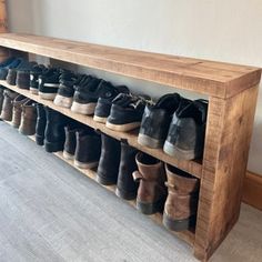 a wooden shoe rack with many pairs of shoes on the top and bottom shelves below