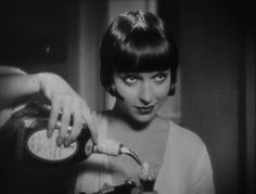 a black and white photo of a woman holding a hair dryer in her hand