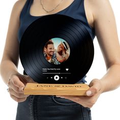 a woman holding up a record with an image of a man and woman on it