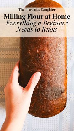 a person holding a loaf of bread with the words milling flour at home everything a beginner needs to know