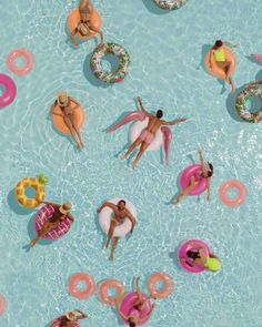 many people are floating in the pool with donuts and float rings on their backs