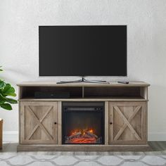 an entertainment center with a fireplace and flat screen tv on it's stand in front of a white wall