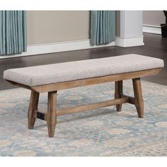 a bench sitting on top of a rug in front of a window with blue curtains