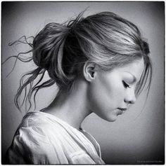 a woman with her hair in a high bun is looking down at the ground while wearing a white shirt