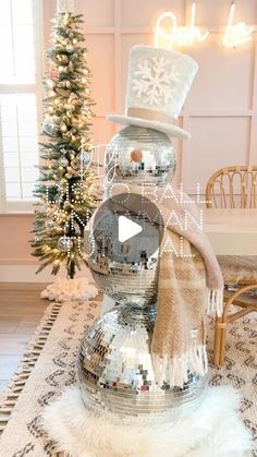 a snowman made out of disco balls on top of a rug in front of a christmas tree