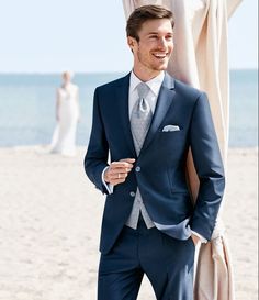 a man in a suit standing on the beach