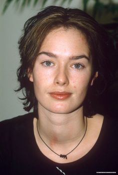 a close up of a person wearing a necklace and looking at the camera with a serious look on her face