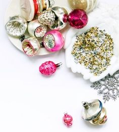 christmas ornaments are arranged on a plate with silver and pink baubles next to them