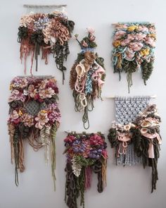 several pieces of art made out of yarn and flowers hanging on a wall with strings