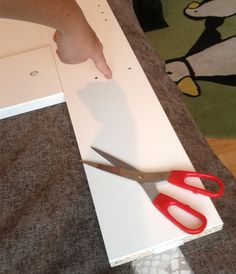 a person cutting paper with scissors on top of a table next to a penguin wallpaper