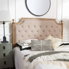 a bedroom with a bed, nightstand and mirror on the wall above it's headboard