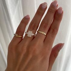 a woman's hand with three different rings on her fingers and one has a diamond in the middle