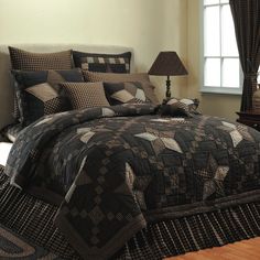 a black and brown quilted comforter set on top of a bed next to a lamp