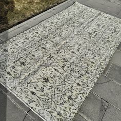 a white and black area rug on the side of a road with grass in the background