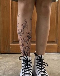 a woman's legs with flowers on them and black laces around the ankles