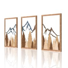 three wood cutouts with mountains and trees in them on a white background, one is showing the mountain range