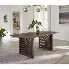 a dining room table with two vases on it and an art piece hanging from the ceiling