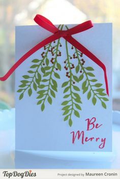 a white card with red ribbon tied around it and the words be merry on it