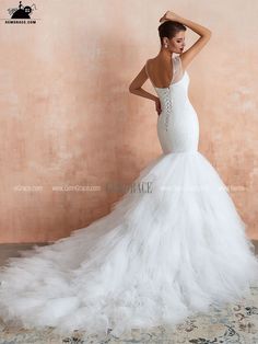 a woman in a white wedding dress standing against a wall with her hand on her head