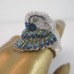 Our paltry pictures cannot EVEN prepare you for the splendor that is this Parrot ring, with its silver tone base and Swarovski stones in clear, blue and green that flash and gleam no matter the light. The ring is a size 7 ¾ and has a pose that's either shy or showboat - you be the judge - and has a nice weight for its size, which is 1.25 inches in length, 1 inch in width and 1.5 inches in height. It is in excellent pre-owned condition and is marked PJM inside the band. So stunning (we do not use Silver Crystal Rings With Jeweled Detail, Silver Jeweled Crystal Rings, Silver Jeweled Ring For Anniversary, Silver Jeweled Rings Made Of Cubic Zirconia, Silver Jeweled Cubic Zirconia Rings, Silver Jeweled Rings With Cubic Zirconia, Peacock Ring, Swarovski Stones, Peridot Stone