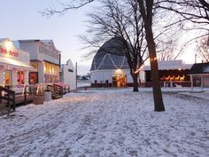 an outdoor christmas market is lit up in the evening with lights and decorations on display