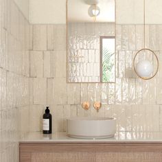 a white sink sitting under a mirror next to a wooden cabinet and counter top in a bathroom