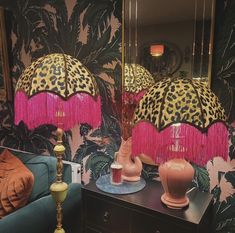 two lamps with pink tassels are on a table in front of a mirror