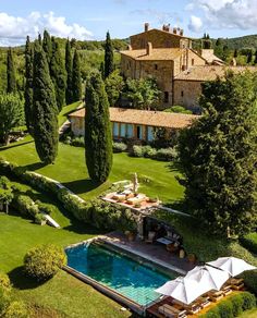 an aerial view of a house and pool in the middle of a lush green field