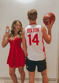 a woman in a red dress standing next to a man holding a basketball