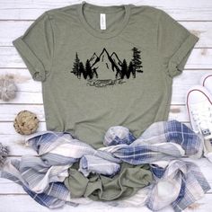 NOTE - ONLY XL  IS AVAILABLE IN PURPLE AT THIS TIME. This cute mountains scene tshirt is a must. We use a high-quality unisex t-shirt that is insanely soft. In fact, it will be one of the softest, best fitting, most comfortable shirts you’ve ever owned.Our shirts are handmade in Ohio by hand with love and care one at a time.We hope you will find a shirt that will inspire you or someone else.DON'T SEE A COLOR OF SHIRT YOU LIKE, FEEL FREE TO CONTACT ME VIA EMAIL AND I WILL DO MY BEST  TO ACCOMMODA Green Crew Neck Shirt For Outdoor Activities, Green Graphic Tee For Camping, Green Graphic Tee For Hiking, Casual Hiking Shirt With Letter Print, Graphic Tee T-shirt With Crew Neck For Hiking, Summer Shirt With Screen Print For Outdoor Activities, Summer Outdoor Shirt With Screen Print, Summer Hiking T-shirt With Screen Print, Summer Outdoor Screen Print Tops