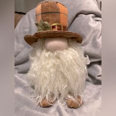 a stuffed toy is wearing a hat and long white hair, while sitting on a blanket