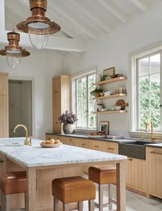 a large kitchen with an island in the middle and two stools at the end