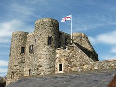 an old stone castle with a flag on top and a blue sky in the background