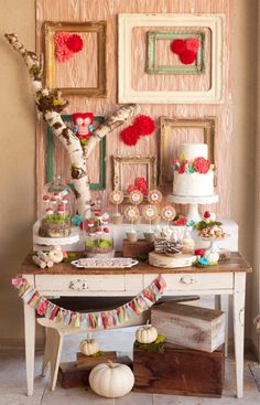 a table topped with cakes and desserts next to pictures on the wall behind it