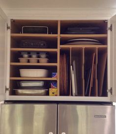 an open refrigerator with dishes and utensils in the bottom shelf next to it