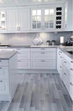 a kitchen with white cabinets and wood flooring on the walls is pictured in this image