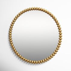 a round gold beaded mirror on a white wall